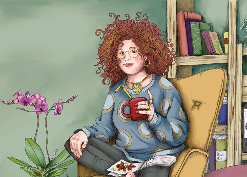 Rothaarige Frau sitzt mit einer Kaffeetasse auf einem Sessel in einem Zimmer. Auf ihrem Schoß liegt ein Buch. Links neben ihr steht eine Orchidee